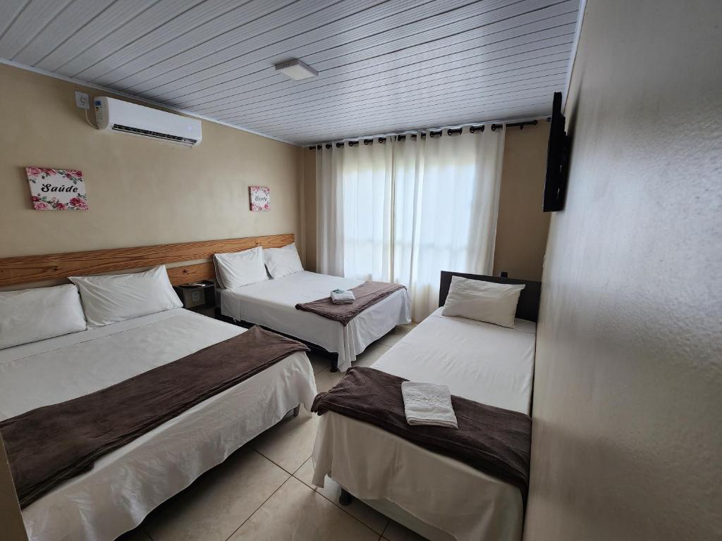 a hotel room with two beds and a window at Pousada King in Vitória da Conquista