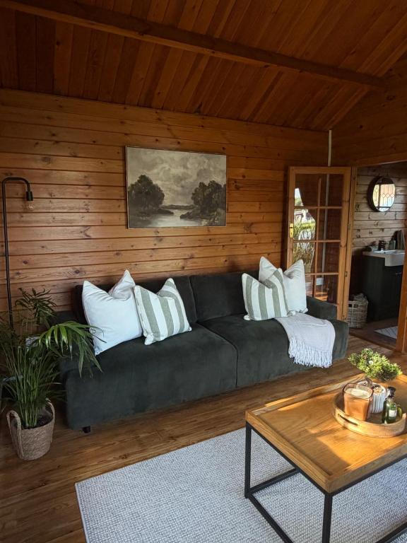 a living room with a black couch with white pillows at Swan cove - Lakeside Caravan Park in Denver
