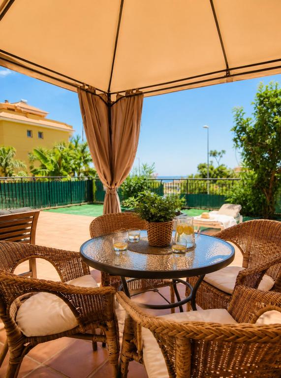 a patio with a table and chairs and an umbrella at Spacious Apartment with Garden & Terrace in Puerto de Santiago