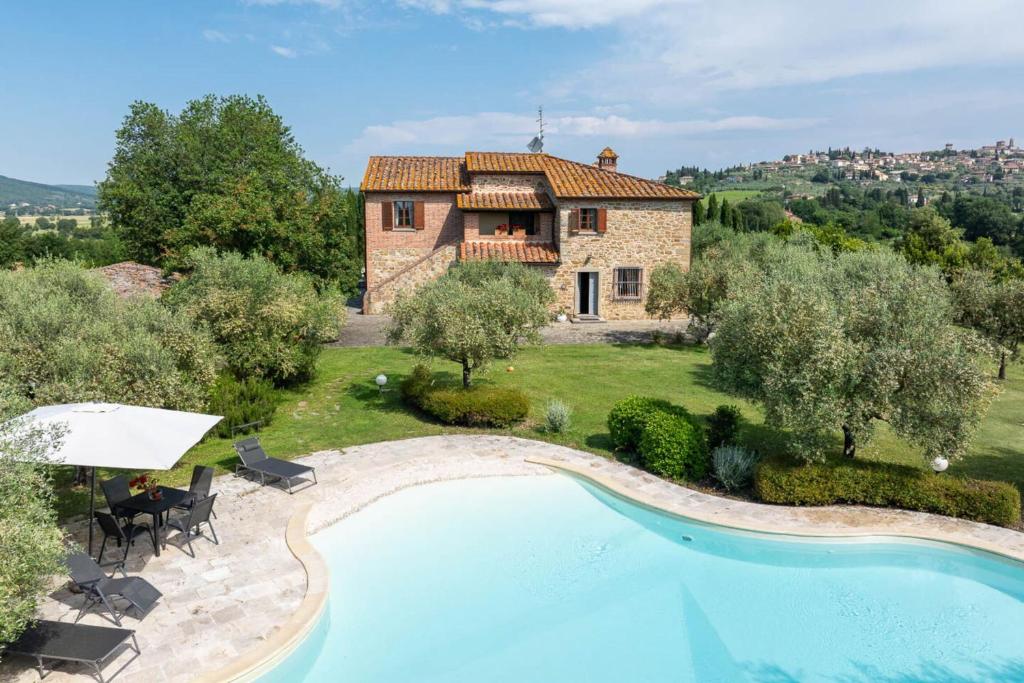 a villa with a swimming pool in front of a house at Podere Il Pozzangone by Geco Vacation Rentals in Lucignano