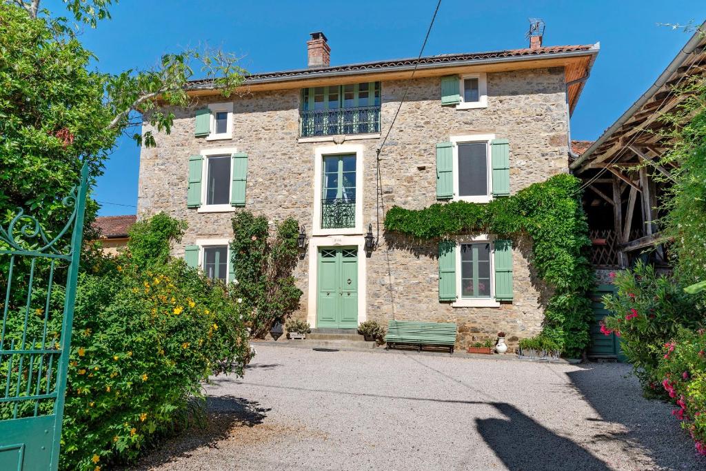 ein Steinhaus mit einer grünen Tür und einer Bank in der Unterkunft Chambres D'hôtes Baladous in Montgaillard-de-Salies