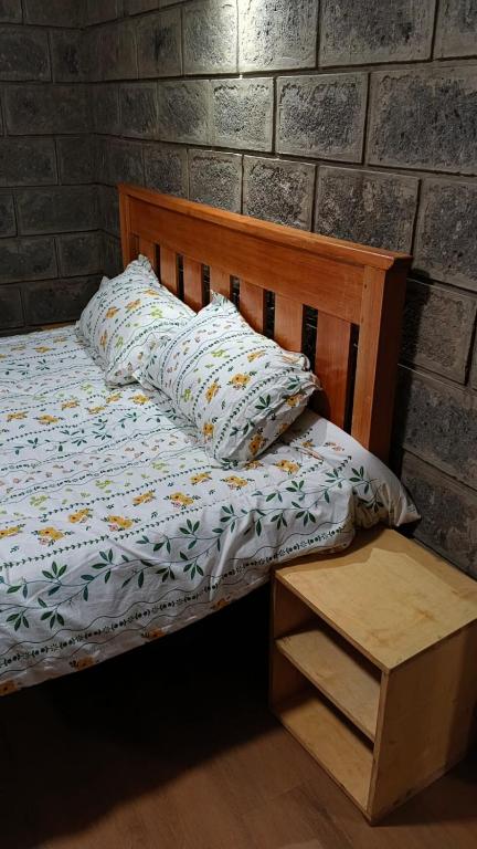 a bed with a wooden headboard and pillows on it at Propost place in Kijabe