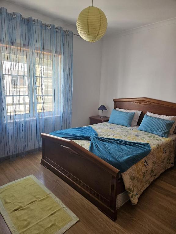 a bedroom with a large bed with blue sheets at BigWaves2 in Nazaré
