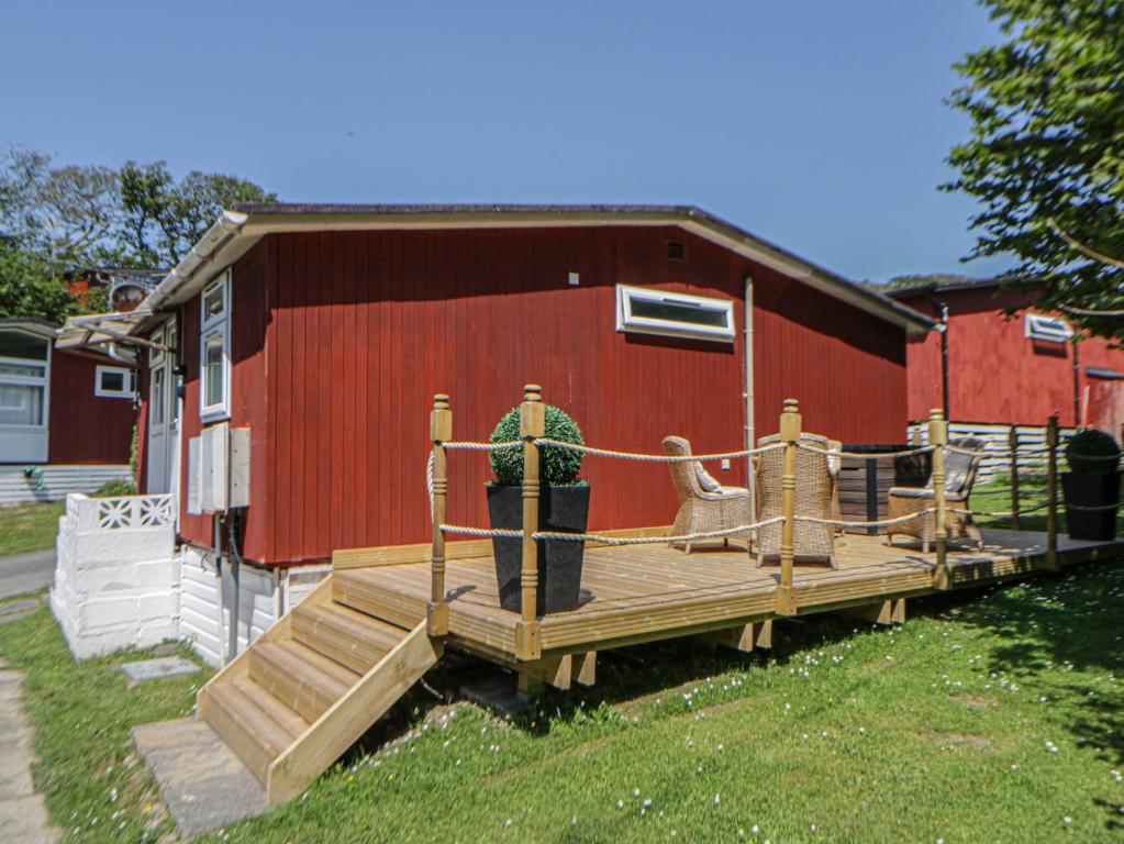 a wooden deck in front of a red barn at Chalet 23 Erw Porthor in Tywyn