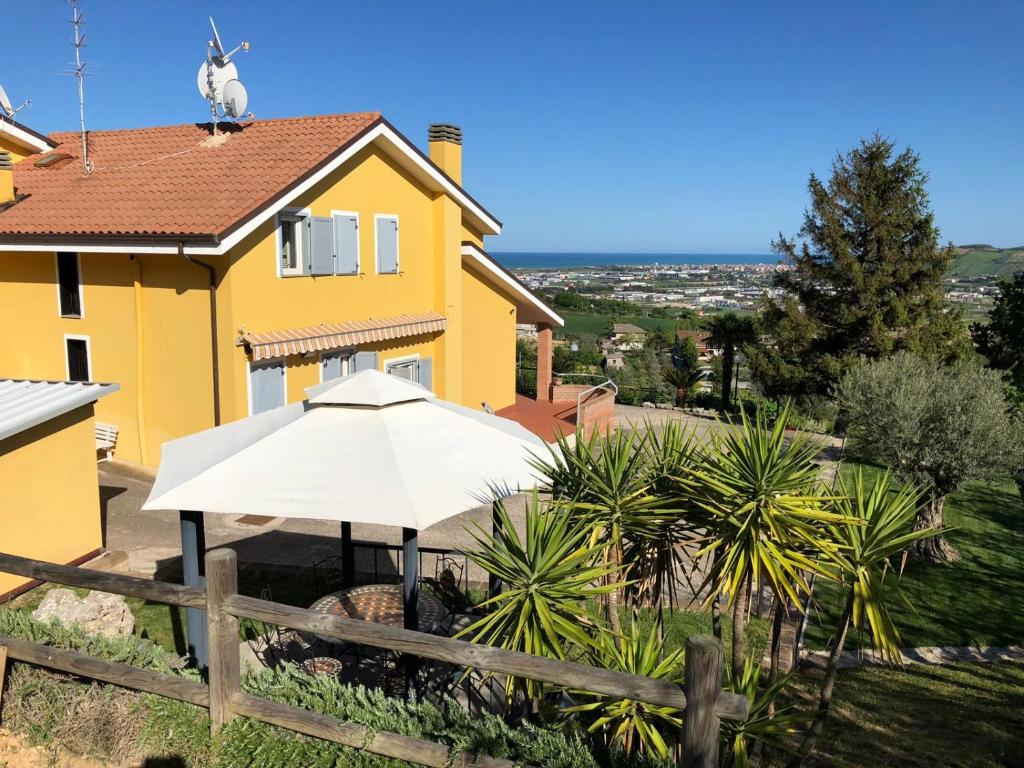 a yellow house with an umbrella in front of it at Villa Maria Giuseppina a San Benedetto del Tronto in Monteprandone