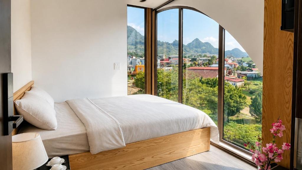 a bedroom with a bed and a large window at Gabi Boutique Hotel in Mộc Châu