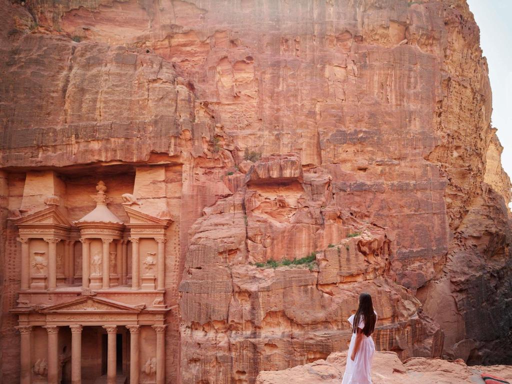a woman standing in front of a rock wall at Mövenpick Resort Petra in Wadi Musa