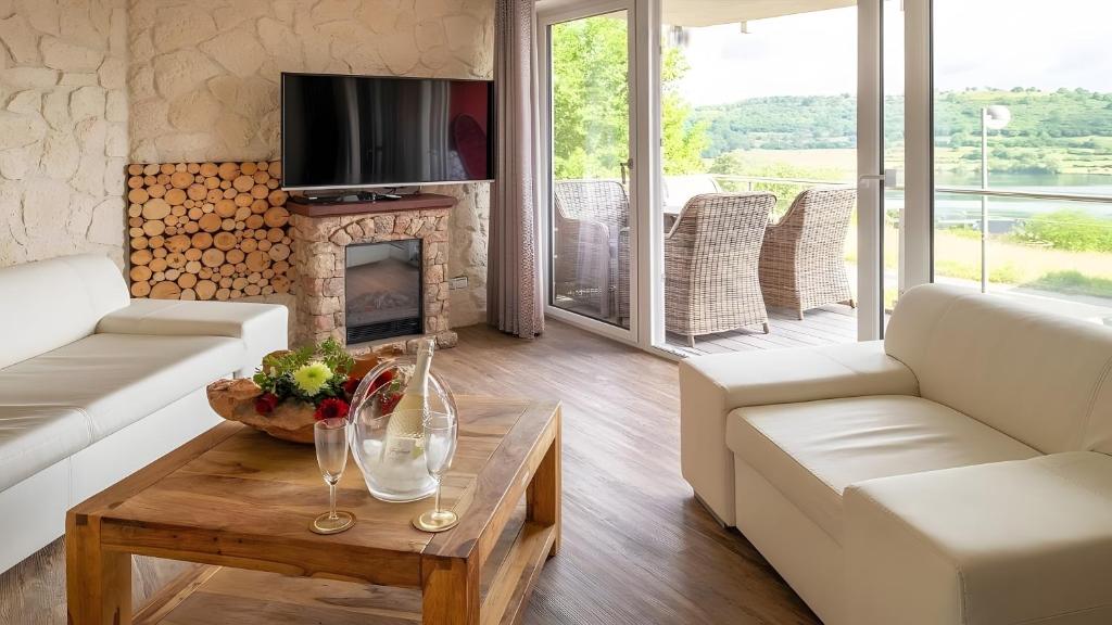 a living room with white furniture and a fireplace at Exclusiv Ferienwohnung Maarpanorama in Schalkenmehren