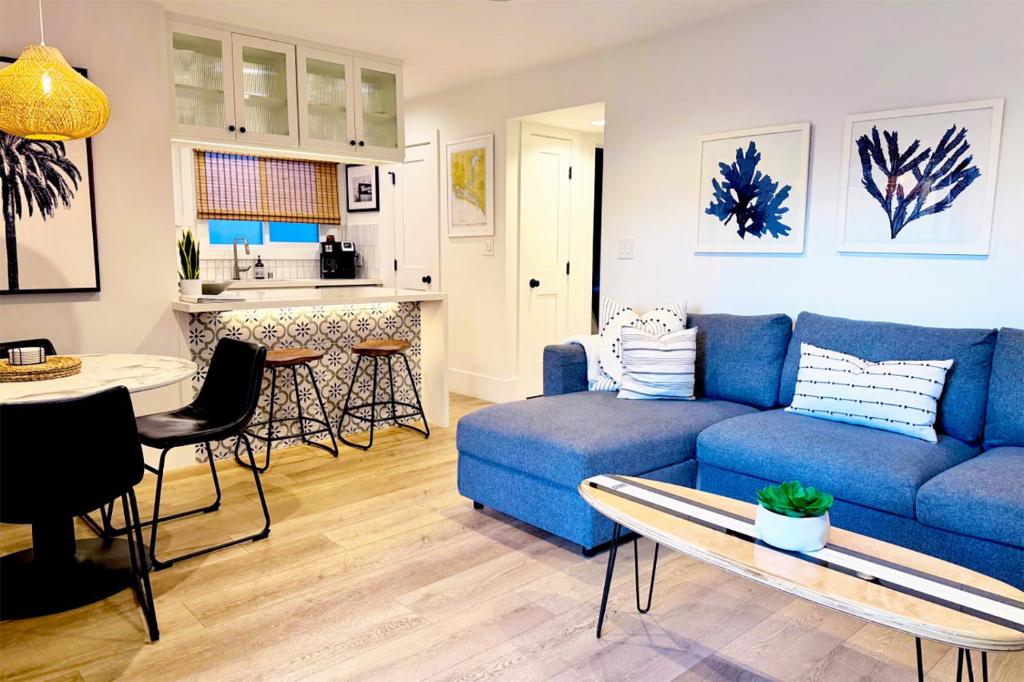 a living room with a blue couch and a table at 2026 Award Winner, Luxe 2BR, steps to sand & pier, with fire pit, AC and parking in Newport Beach