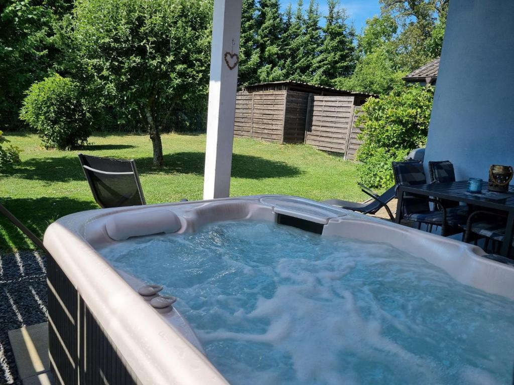 a hot tub on a patio with a table and chairs at Eifel Dream Wildeiche in Fleringen