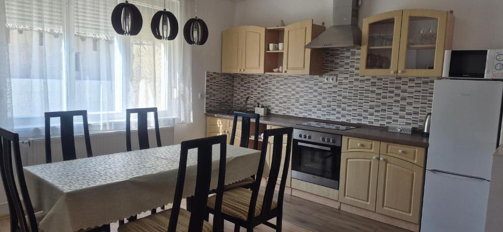 a kitchen with a table and a white refrigerator at Akácfa Vendégház in Makó