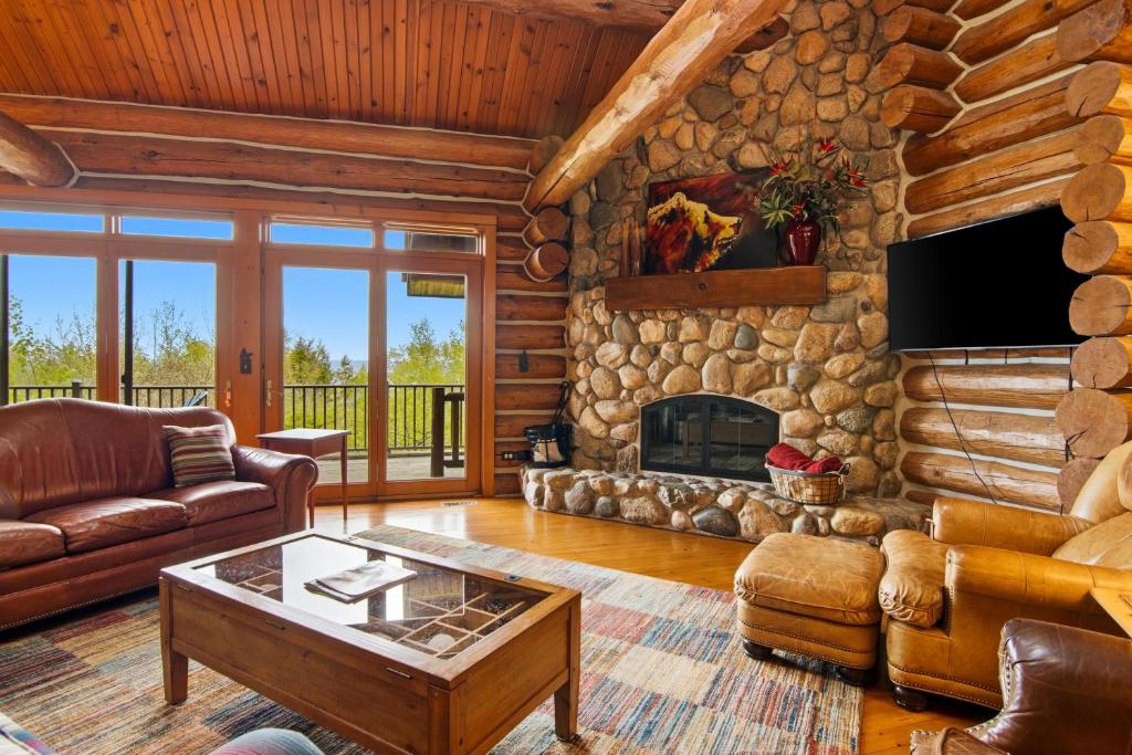 a log cabin living room with a stone fireplace at Viewtopia in Suttons Bay