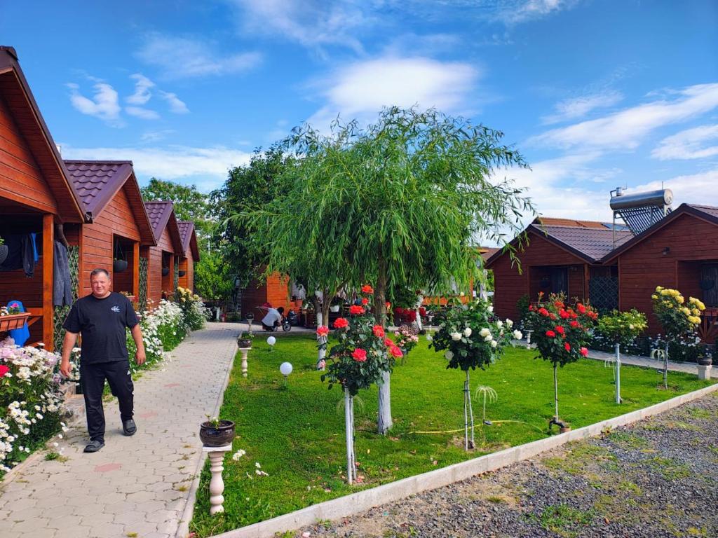 a man walking through a garden with trees and flowers at Cabanele Deltei in Dunavăţu de Jos