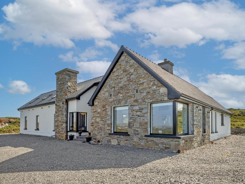 a stone house with large windows on a driveway at Sweet Garden in Ballyconneely