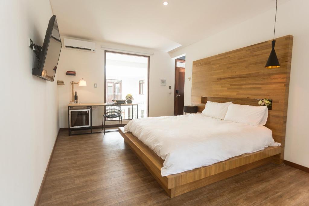 1 dormitorio con 1 cama grande y cabecero de madera en Cosmopolitano Hotel Boutique, en Santa Cruz de la Sierra