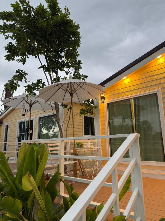 a house with an umbrella on a deck at วันรีสอร์ท in Ratchaburi