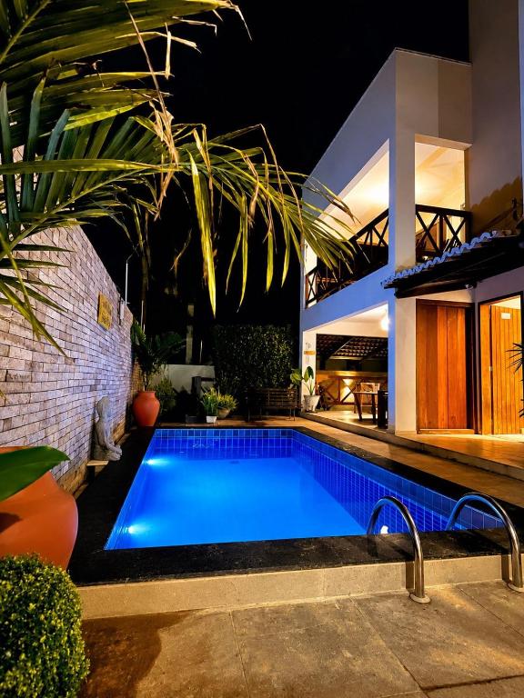 a swimming pool in front of a house at night at Condomínio Harmonia in Pipa
