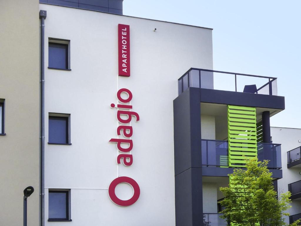 a white building with a red sign on it at Aparthotel Adagio Bâle Mulhouse Aeroport in Blotzheim