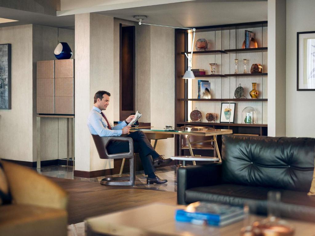 a man sitting at a table reading a book at Fairmont Quasar Istanbul Hotel in Istanbul