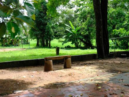 a stone bench in a park with trees and grass at Warriam Road in Chottanikara