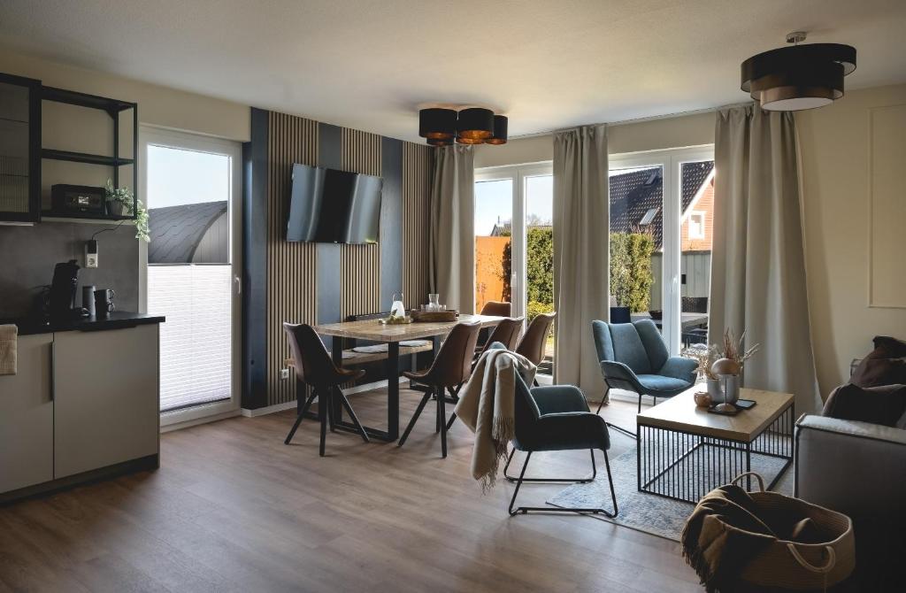 a kitchen and living room with a table and chairs at Design-FeWo Fleesensee, Wallbox, Sauna, Terrasse in Unter Göhren