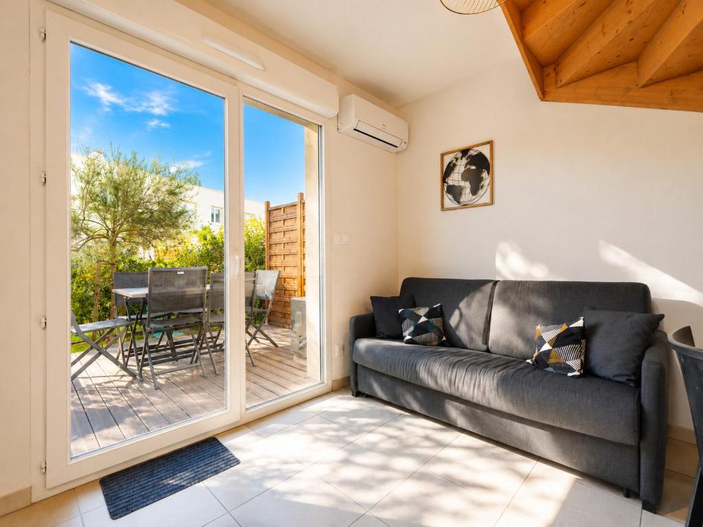a living room with a leather couch and a sliding glass door at La Dune 38 - Villa 3P6 in Valras-Plage