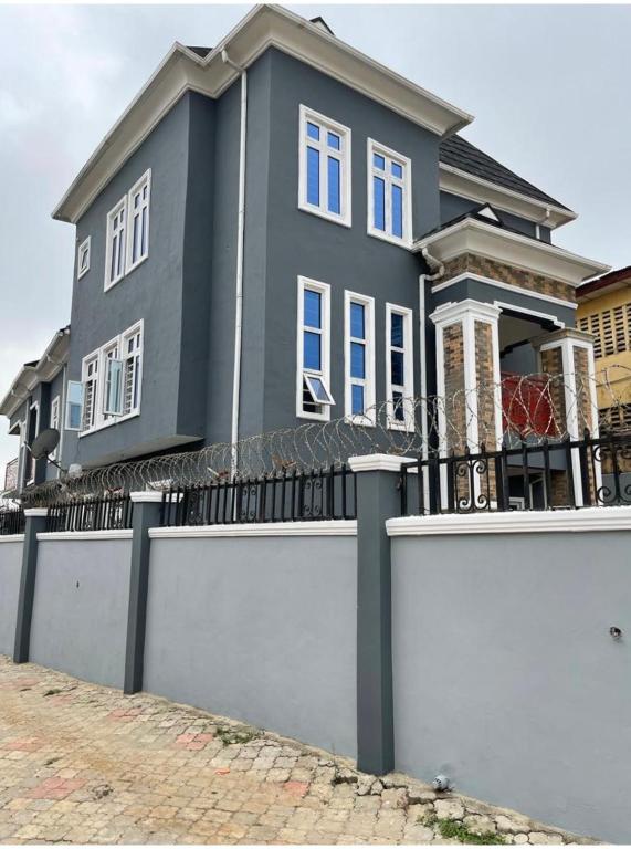 a grey house with a white fence in front of it at Sbk3apartments in Ologode