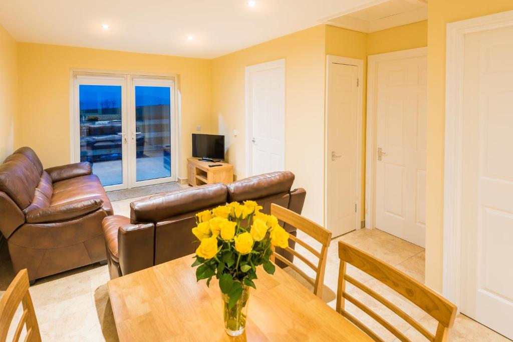 una sala de estar con una mesa con flores amarillas. en Elagh Cottages, en Derry Londonderry