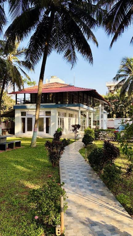 a large white building with a palm tree in front at Niwas Villa in Vihur
