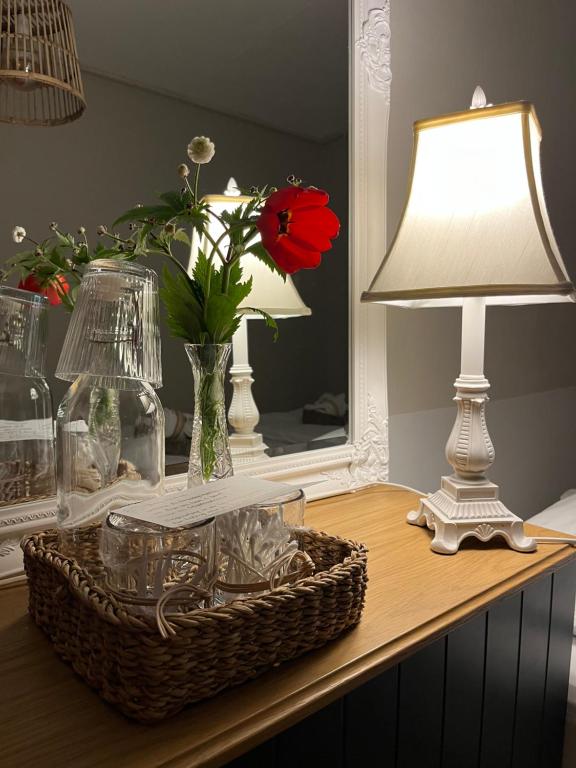 a table with a lamp and a vase with a red flower at Homestay Snæfellsnes in Stykkishólmur