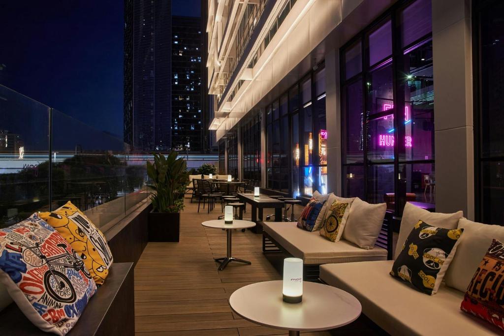a building with couches and tables on a balcony at night at Moxy Shenzhen North Station in Shenzhen