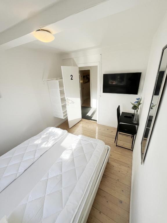 a white bedroom with a white bed and a desk at Central Large Double Room with free parking in Aalborg
