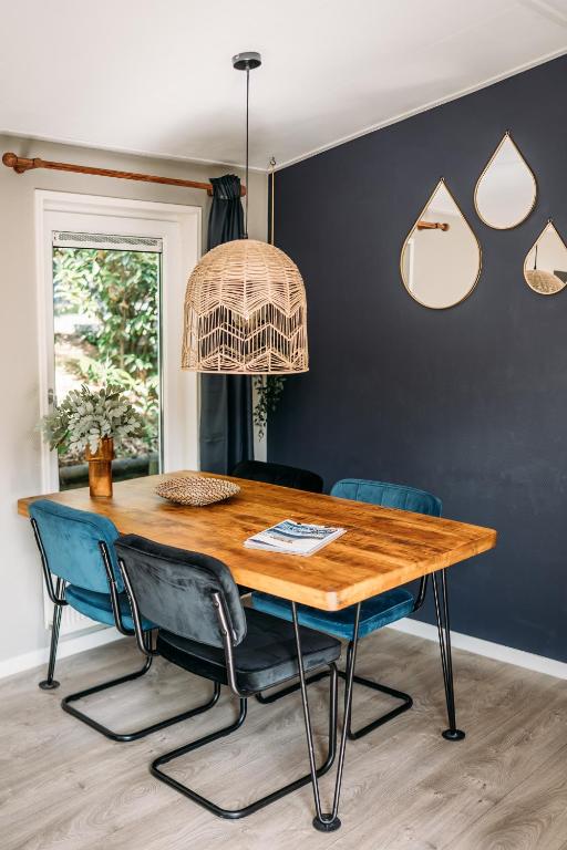 a dining room with a wooden table and blue chairs at Forrest Lodge in bosrijke omgeving de Veluwe - met terras, tuin en fietsschuurtje in Nunspeet