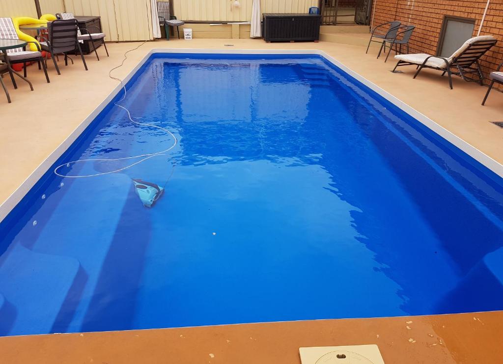 a blue swimming pool with chairs and tables at Traplins Accomodation in Lakes Entrance