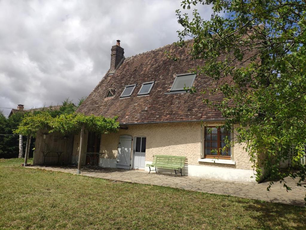 a house with a green bench in front of it at Charming cottage in Boursay