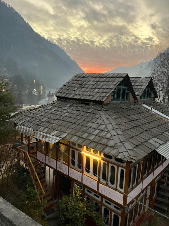 a house with a shingled roof on top of it at Parma Guest House in Kasol