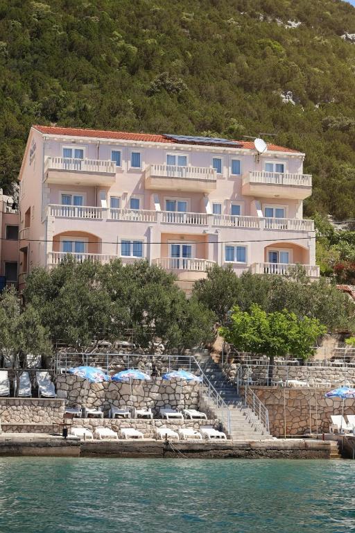 a large building with chairs and umbrellas next to the water at Villa Ancora in Neum