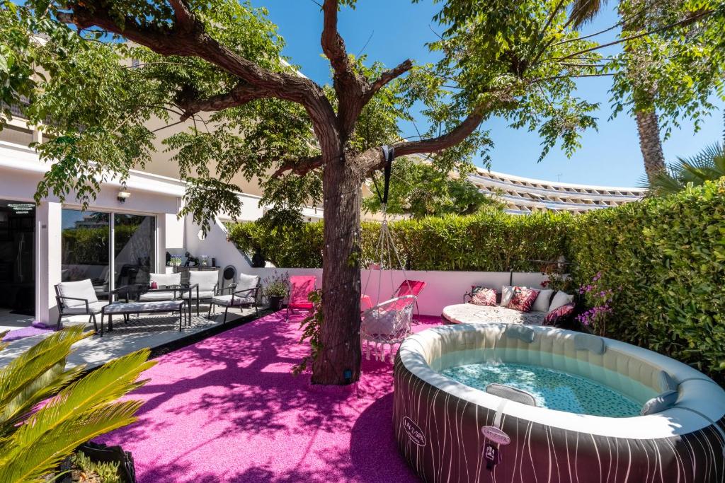 a garden with a hot tub and a tree at Villa L'Hyliadenna avec jardin - parking privé - au cœur du Village Naturiste, NaturaBeach Héliopolis - Plage à pied in Cap d'Agde