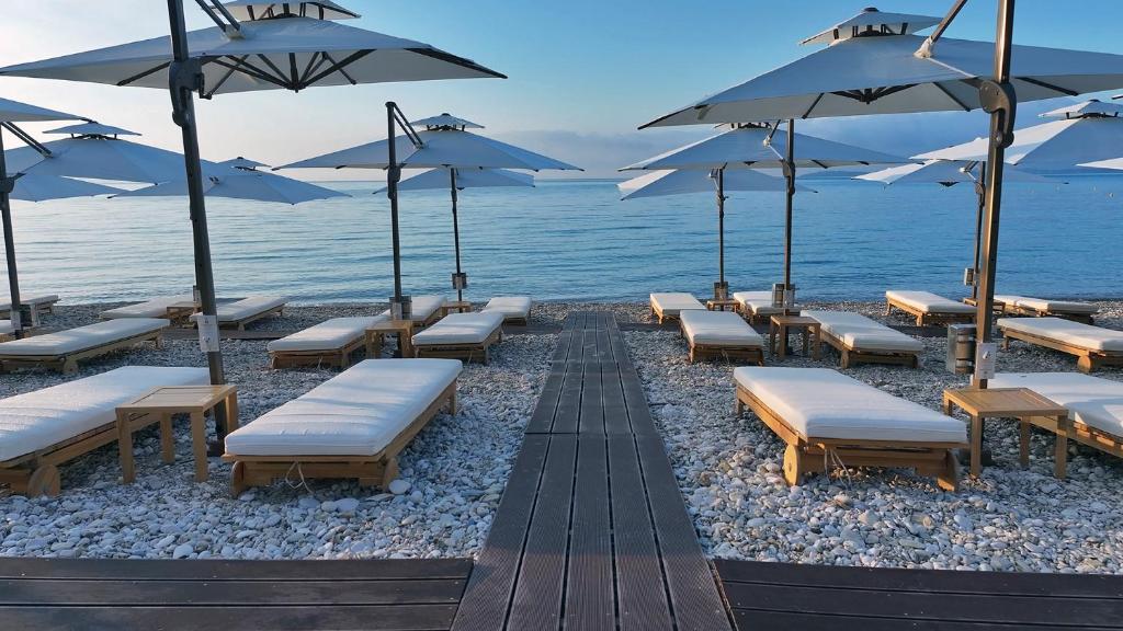 a row of lounge chairs and umbrellas on a beach at Ionian Crown Suites in Barbati in Barbati