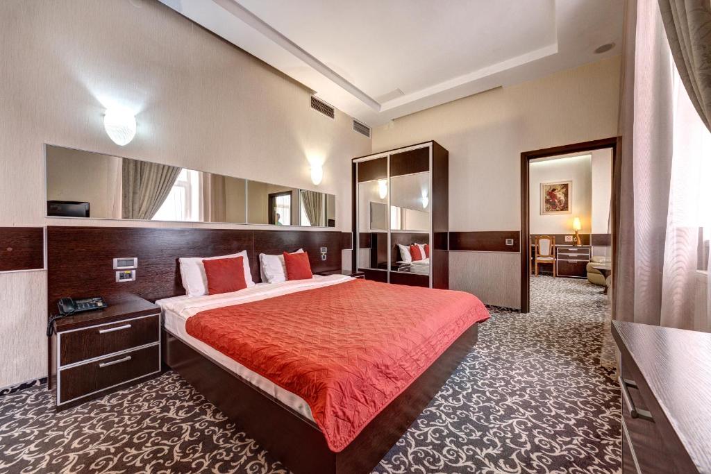 a hotel room with a bed with a red bedspread at Terra Nova Spa Hotel in Hatne