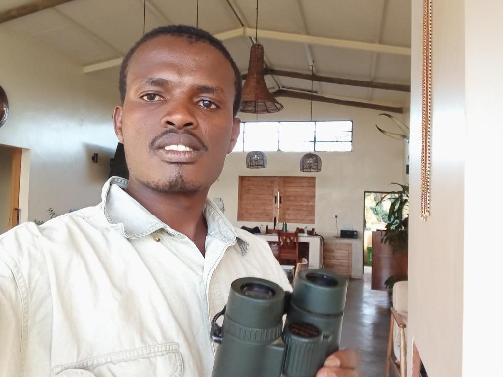 a man holding a pair of binoculars at Turacova Safaris & Accommodation in Mara Simba