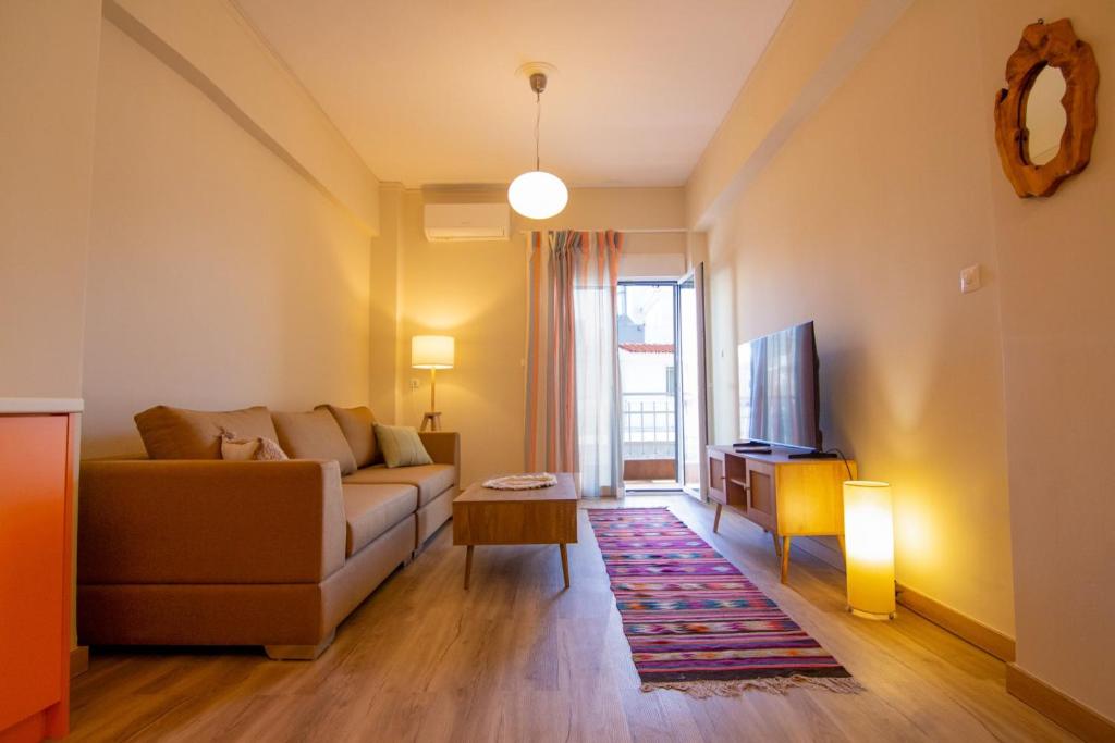 a living room with a couch and a tv at MC4 Residences in Loutraki