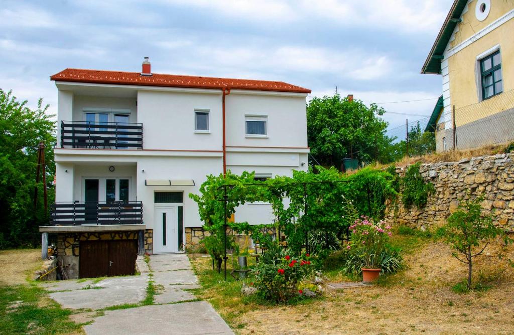 a white house with a fence and a stone wall at Privet Apartman in Balatonfüred