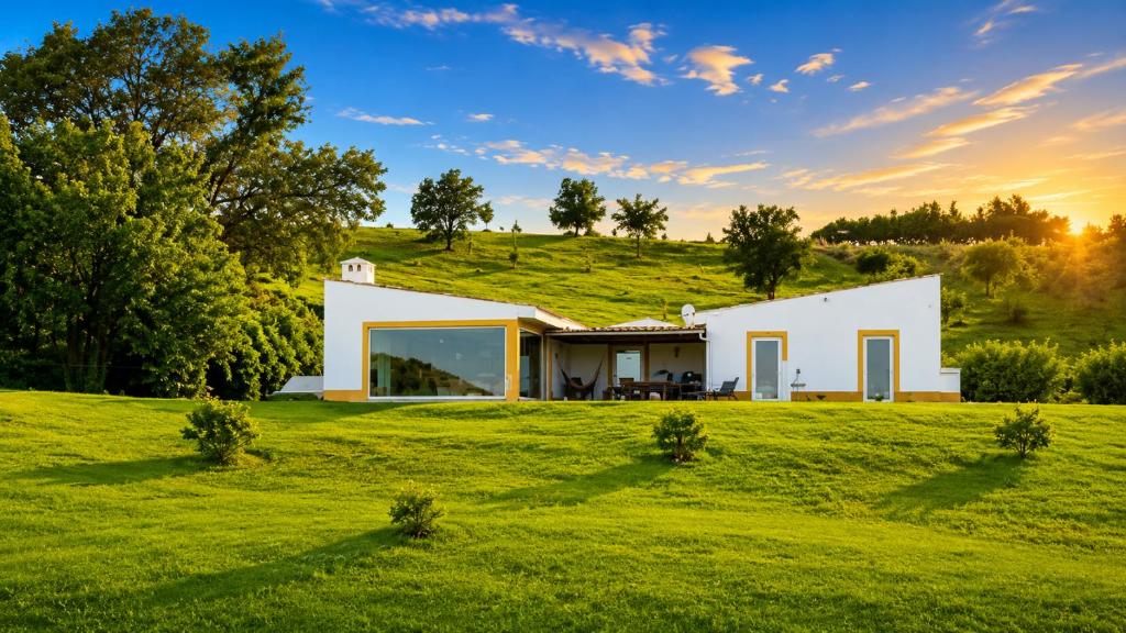 a white house on a hill with a green field at Pouso Du'Vagar in Cuba