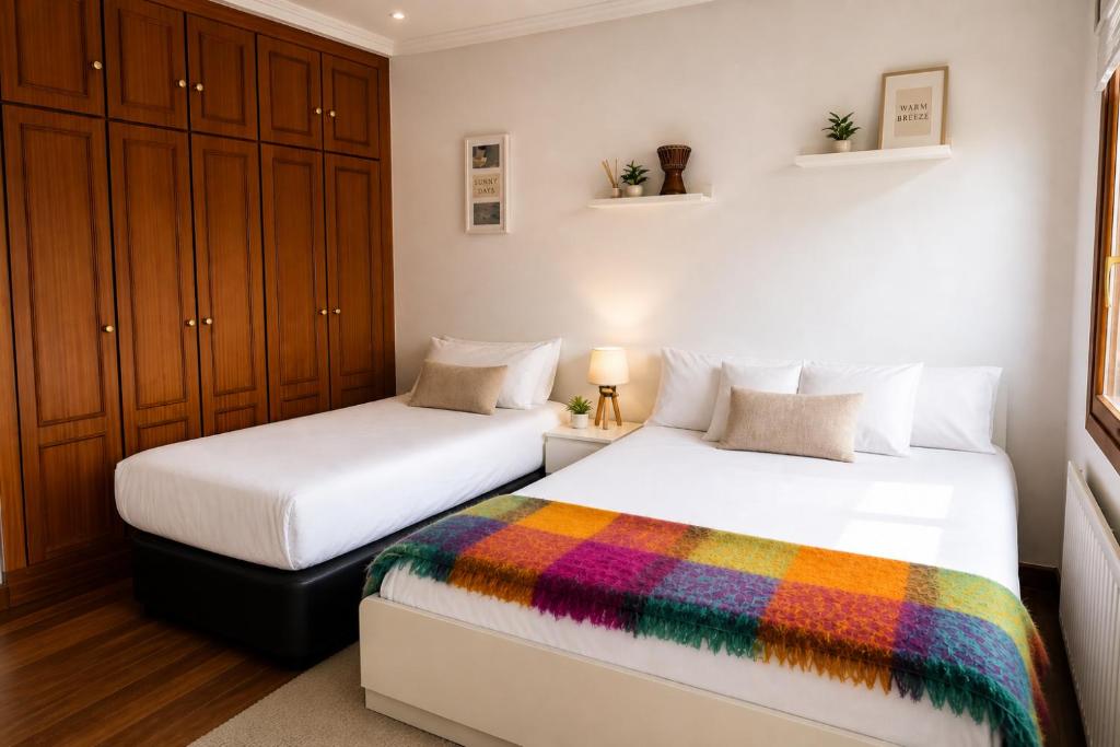 two beds in a small room with a rainbow blanket at Chalet Bilbao-Aeropuerto in Sondika