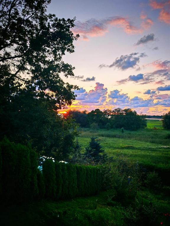 a sunset in a field with a fence and trees at Wczasy z Wędką in Gardna Wielka