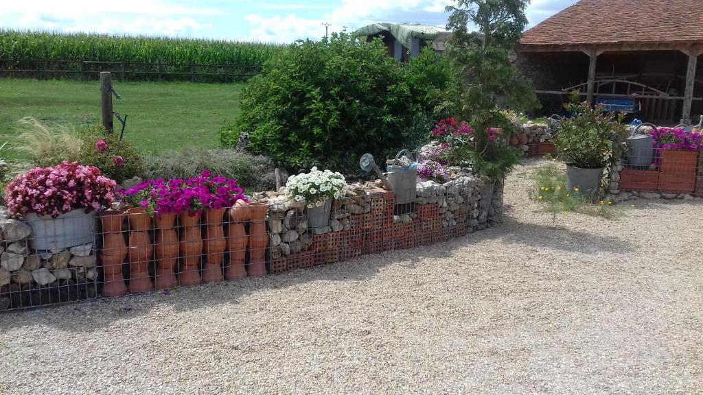 a retaining wall with pots of flowers and plants at Chbres D'hôtes Ferme De Champliveau in Bonnée
