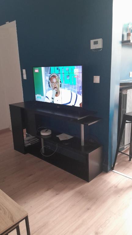 a flat screen tv on a black stand in a living room at Maison Conviviale amiens in Amiens