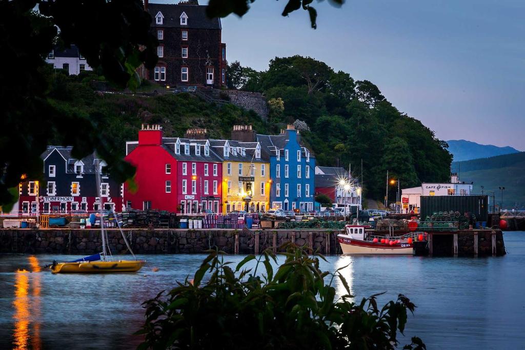 a group of colorful buildings next to a body of water at Mishnish Hotel in Tobermory