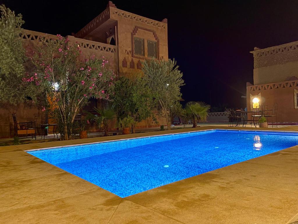 a large blue swimming pool at night at Riad Hassi Labied Merzouga in Merzouga